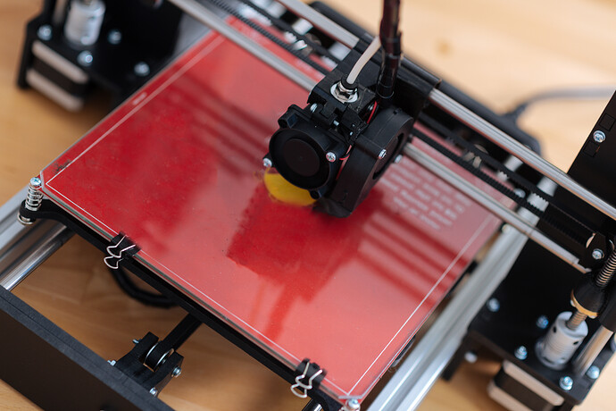 Close-up of a 3D printer nozzle laying down molten filament during a print