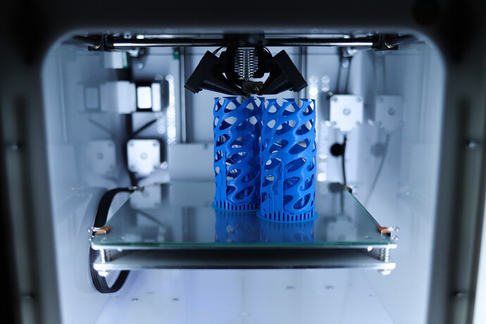 Close-up of a 3D printer hot end extruding plastic filament